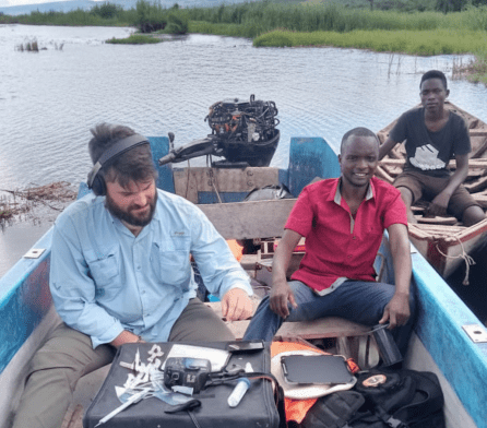 PhD student Matthew Peroš and Thomas (a local field assistant) are pictured in a boat on Lake Tanganyika in Zambia, They are photographing cichlids.