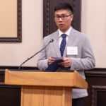 Guoshen talking into a microphone on a podium.