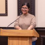 Nabila talking into a microphone on a podium.