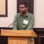 Sagar talking into a microphone on a podium.