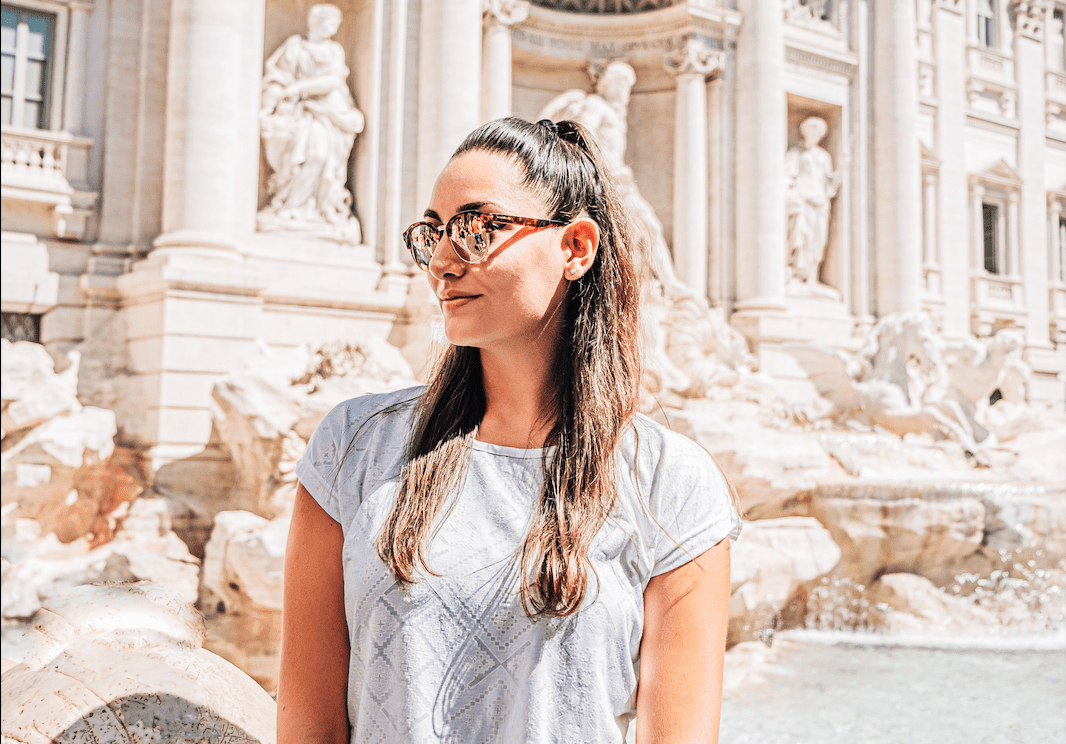 A person standing in the foreground smiling towards to the camera with a scenic view of Florence Italy in the background.