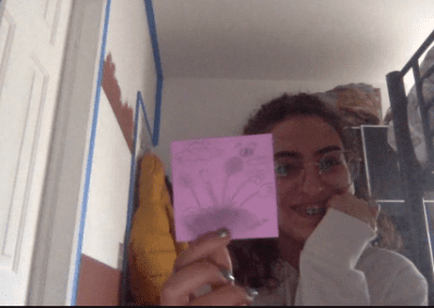 A person holding up a drawing on a post-it note.