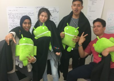 Four students holding the Android stuffed animal mascot.