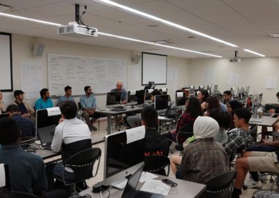 The Cohort 1 students sitting by their computers in a computer lab listening to the lecture.