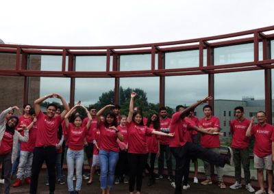 Group photo of Cohort 1. Some of the students are holding their arms up into different shapes.