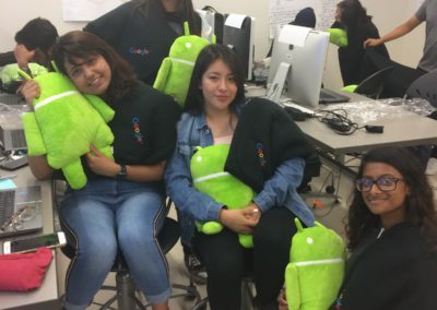 Four students holding the Android stuffed animal mascot while posing for the photo.