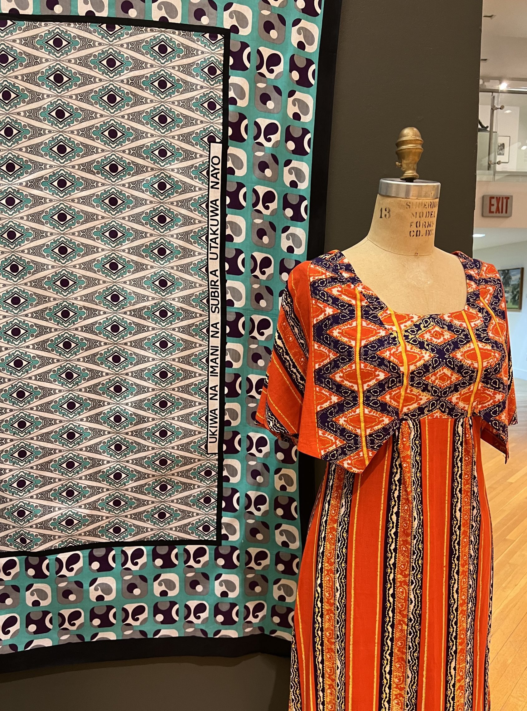 5 IMG_1485 The multicolored Kanga dress next to Kanga textiles at a exhibit.