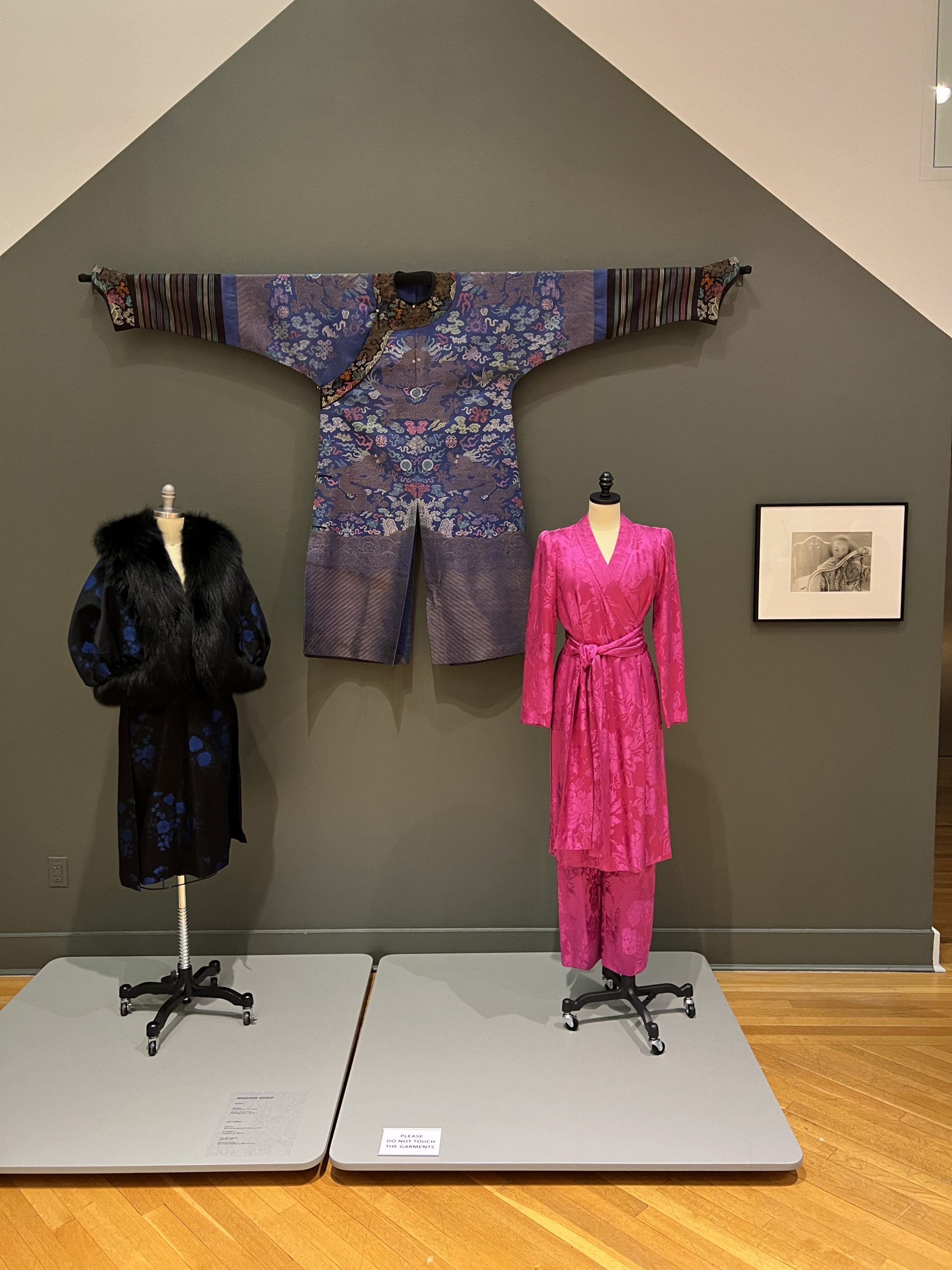 4 Chinese YSL Brocade Brocade silk collection at an exhibit. From left to right: A 1960s blue and black two piece ensemble, A blue Chinese robe from the Qing dynasty, and a hot pink two piece ensemble.