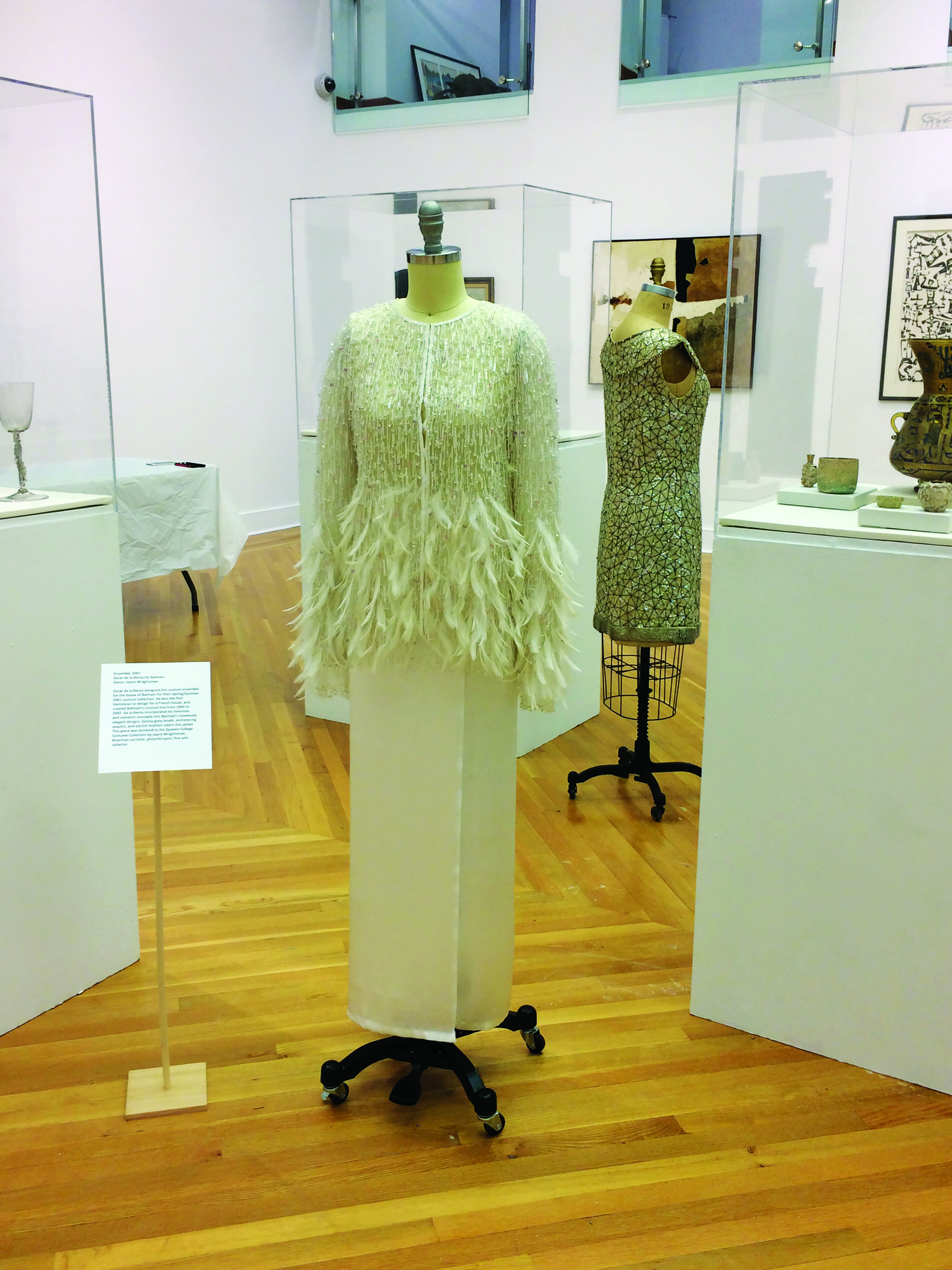 A dress of pale green, beaded bodice with feathers at the waist to hem feathers displayed at the campus's museum.