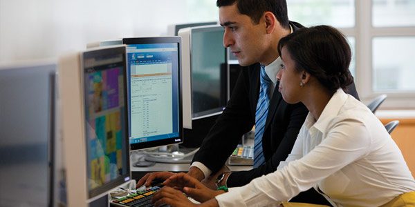 Two people working at a computer together.