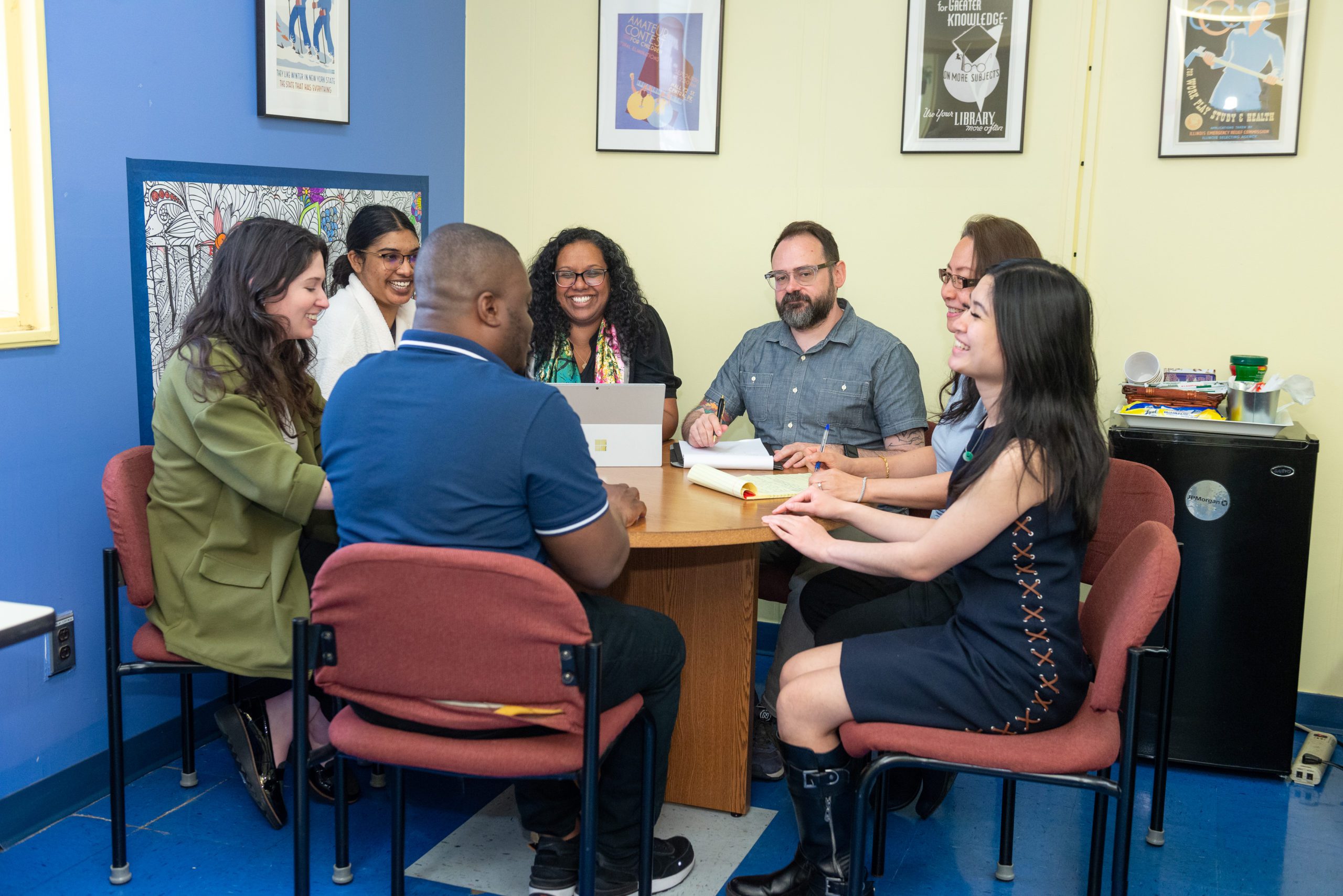 A person sitting at the right-hand side of the table shakes hands with someone who is standing across from them.