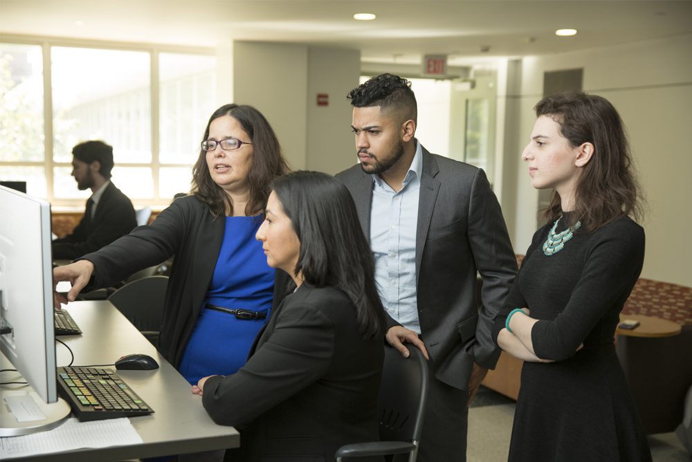 A group of people standing around a computer.
