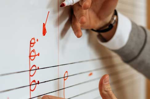 Hands teaching music notation on a whiteboard