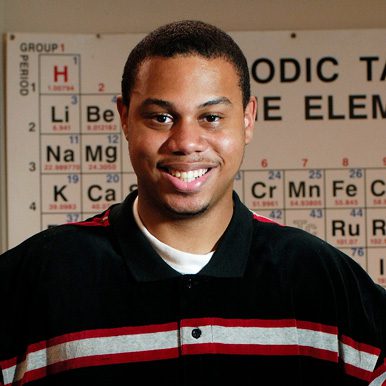African American man smiling with periodic table in background