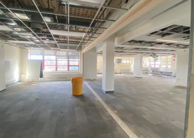 Renovations in progress of an empty room with missing panels in the ceiling.
