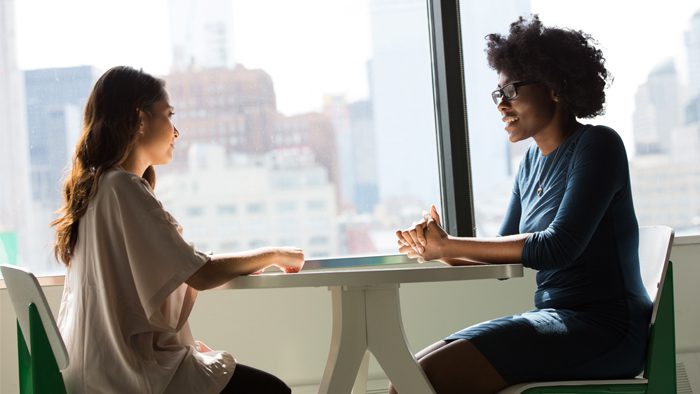 Two people sitting at a table and talking.