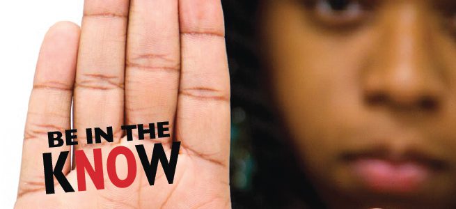 A woman holds up her hand, palm facing the camera with her fingers held together. “Be in the Know” is written in the on her hand.