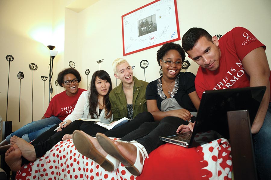 Five people looking at a laptop together.