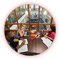 Three people sitting at a table with books.