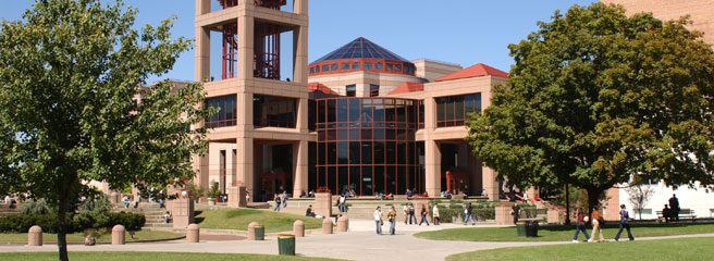 Two students walking through the Queens College Campus. The text at the top of the image reads “Find your own path through exceptional education”.