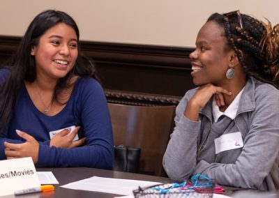 Two people sitting next to each other having a conversation while smiling.
