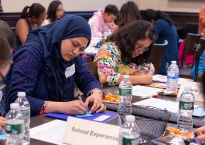 A group of people siting at a table taking notes.