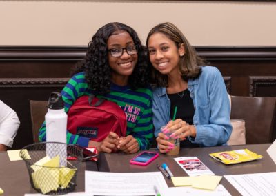 Two people sitting next to each other smile and pose for the camera.