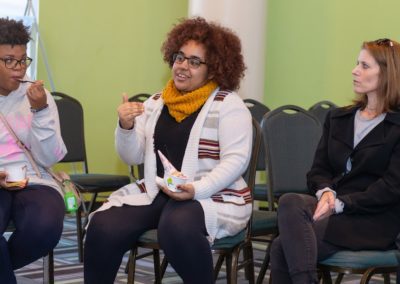 Three people sitting in chairs next to each other having a conversation.