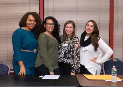 Four people standing together behind a table smiling at the camera.