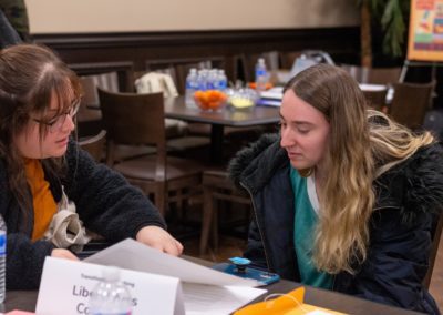 Two people sitting at a table together looking at a paper.