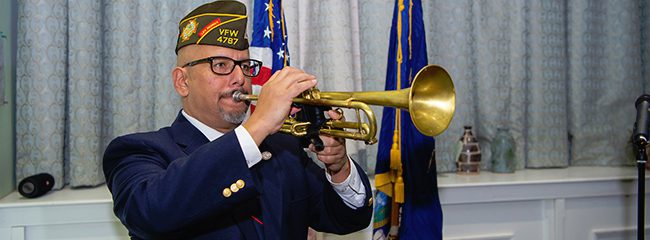 A man in uniform plays the trumpet.